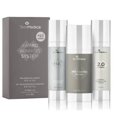 Three SkinMedica skincare products—TNS Essential Serum, HA⁵ Rejuvenating Hydrator, and Lytera 2.0—stand beside their box labeled "Award Winning System.