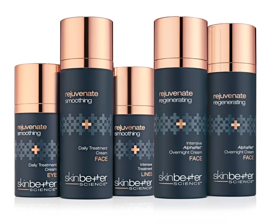 Five Skinbetter Science skincare bottles with dark blue bodies and rose gold caps, labeled as rejuvenate smoothing and regenerating treatments for eyes and face.