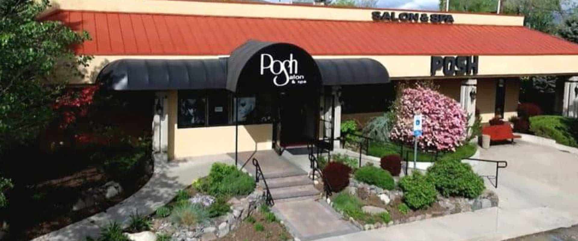 Exterior view of Posh Salon & Spa with a black awning, landscaped entrance, red bench, and accessible parking sign.