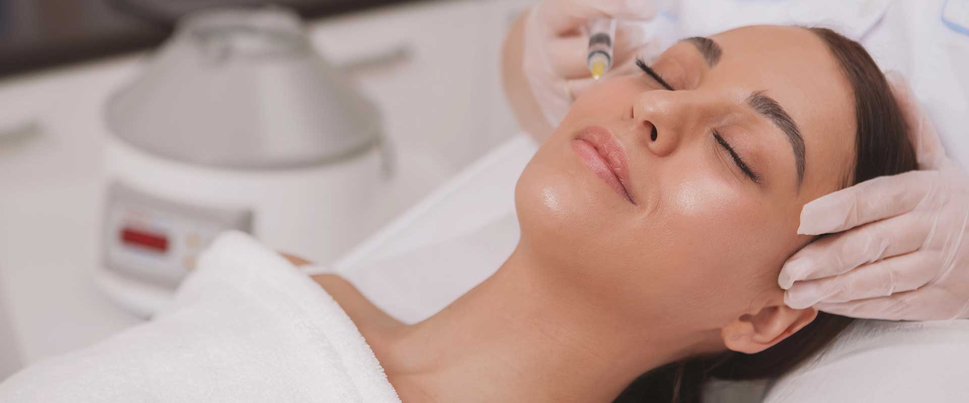 A person with closed eyes receives Sculptra fillers from a gloved professional in a clinical setting.